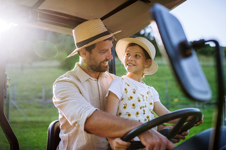 Ein Vater fährt mit seiner Tochter Traktor.